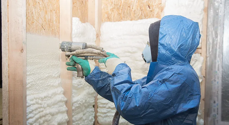 Insulation contractor spraying foam into a stud bay